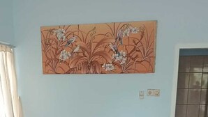 A room with a bed, a wall-mounted painting, a window with curtains, and a tiled floor. - Hepi Bungalow Lovina Bali (Buleleng)