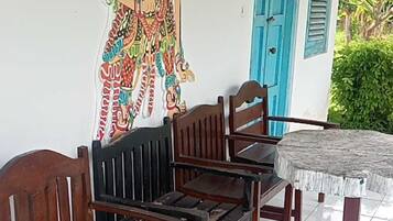 Um banco de madeira com estrutura metálica, uma porta azul e uma parede com um mural colorido.
