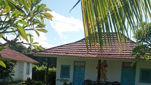 A house with a tiled roof, a front porch, and a grassy yard. - Hepi Bungalow Lovina Bali (Buleleng)
