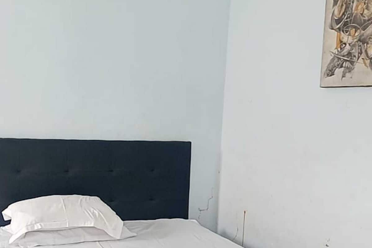 A bedroom with a bed, a headboard, a wall-mounted artwork, and a tiled floor.