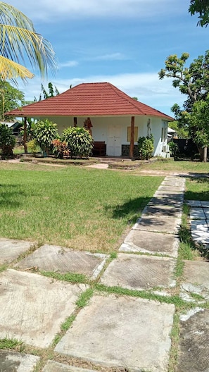 Una casa con techo rojo, un porche delantero y un jardín.