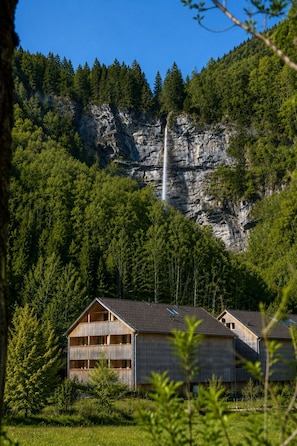 A cabin with a view of a waterfall, surrounded by forest.