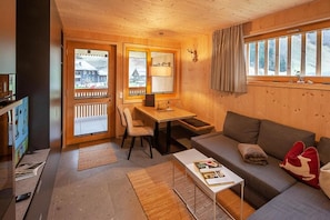 A cozy room with a wooden interior, a sofa, a table, and a chair.