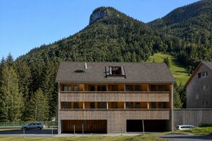 A modern two-story building with a sloped roof, large windows, and a garage. - Eichen Lodge Mellau (Mellau)