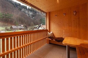 A wooden balcony with a view of a mountainous landscape, a bench, and a table. - Eichen Lodge Mellau (Mellau)