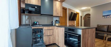 A compact kitchen with wooden cabinets, a built-in microwave, a dishwasher, and an oven.
