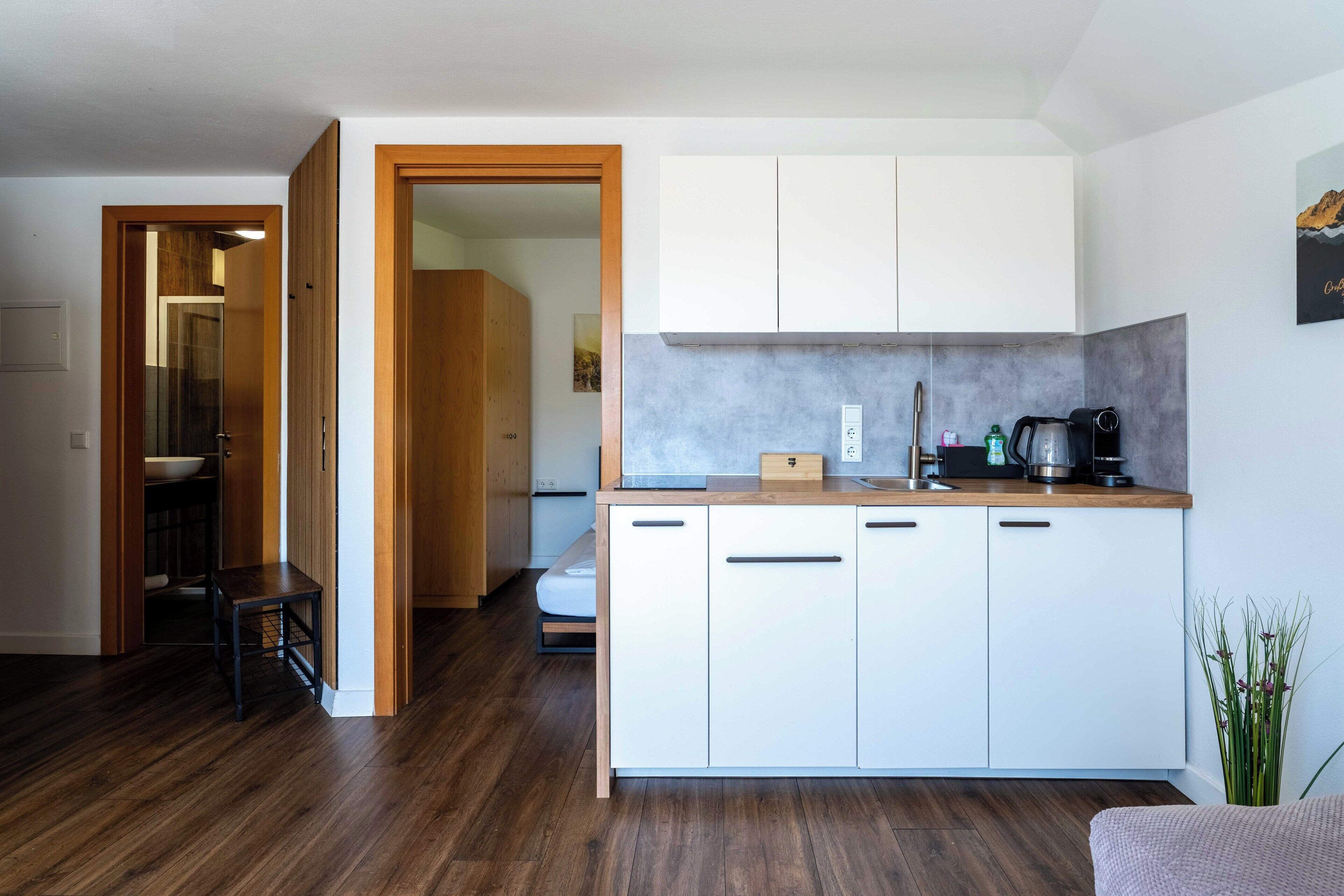 A modern kitchen with white cabinets, a wooden countertop, and a built-in stove.