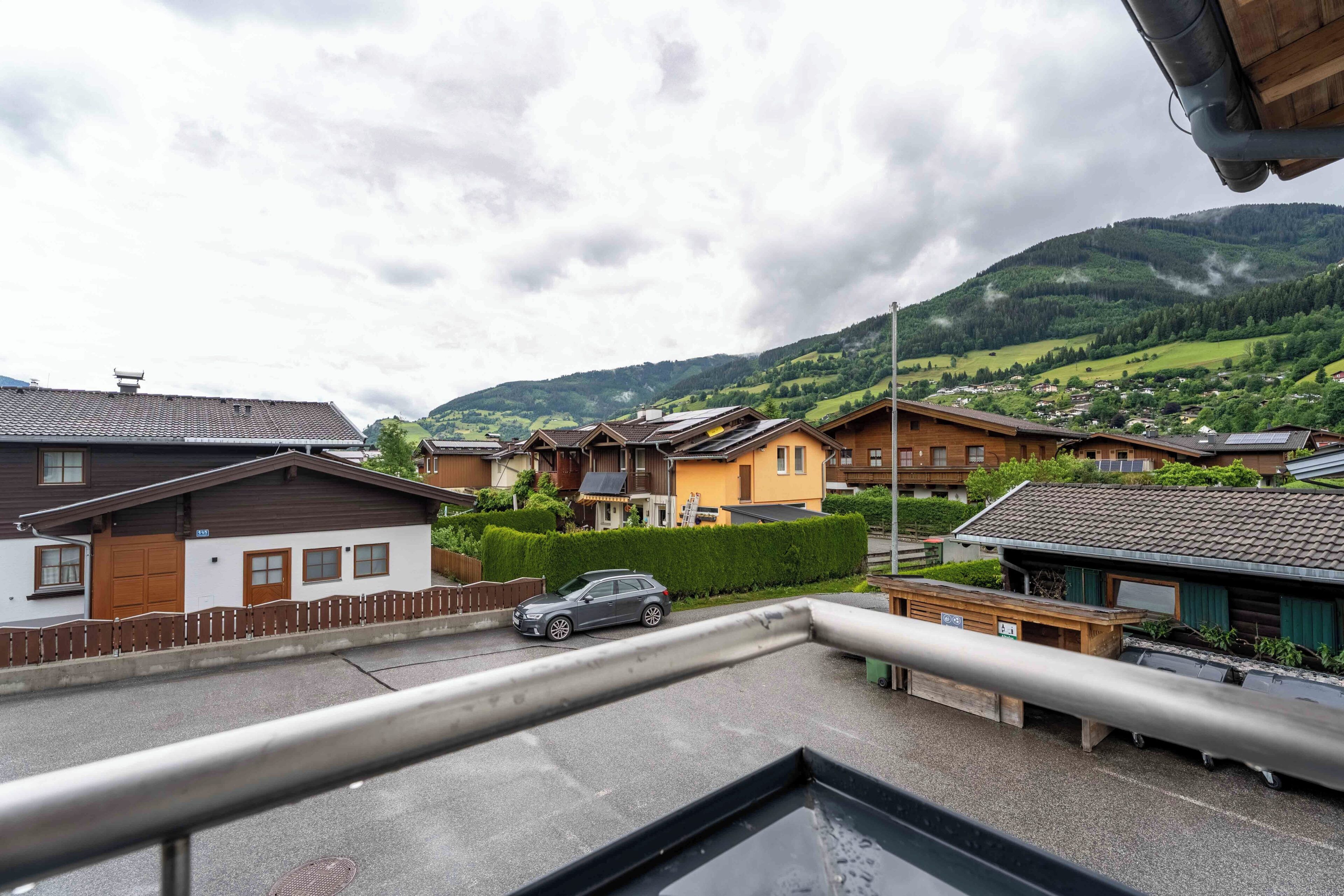 Un quartiere residenziale con case, un'auto e una montagna sullo sfondo.