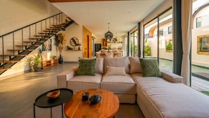 A modern living room with a sofa, coffee table, and a staircase. - K Club Cemagi Villa 5 (Badung)
