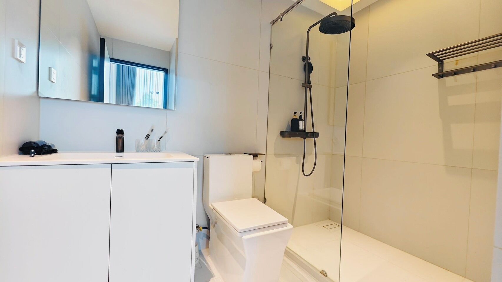 A modern bathroom with a toilet, a shower, and a sink.