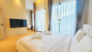 Quarto de hotel com uma cama grande, uma televisão de tela plana na parede e vista para o exterior pela janela.
