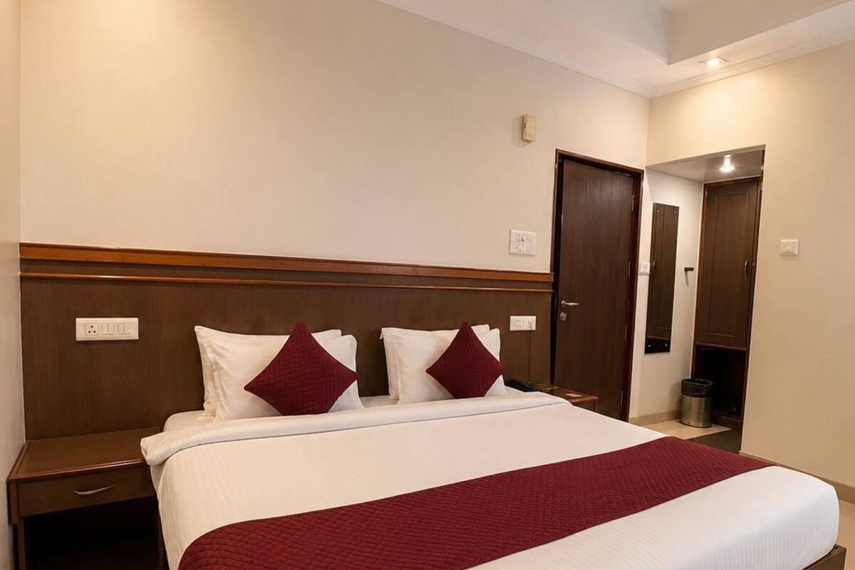 Habitación de hotel con una cama grande, cabecera de madera, mesitas de noche, ventilador de techo y una puerta que da a otra habitación.