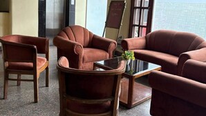 Una hall con un divano, poltrone, un tavolino da caffè e una bacheca.