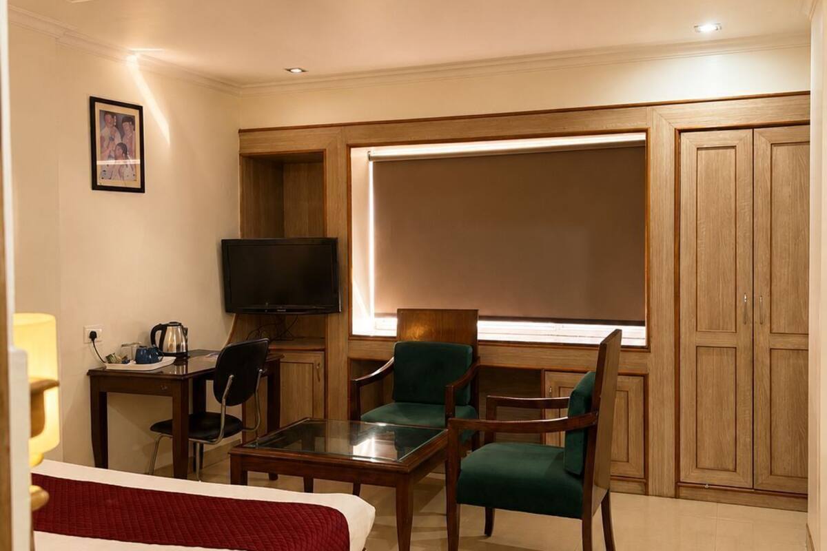 Habitación de hotel con cama, escritorio con computadora, televisor y ventana grande.
