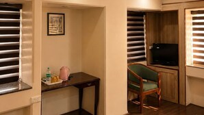 Una stanza con ventilatore a soffitto, televisione, una poltrona verde, un tavolino e un quadro appeso al muro.