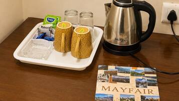 A tray with a kettle, two patterned mugs, and tea packets on a wooden table.