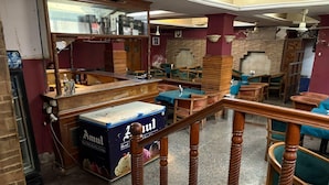 Una stanza con un bancone in legno, una scatola con l'etichetta 'Amul' e una scala con ringhiere in legno.