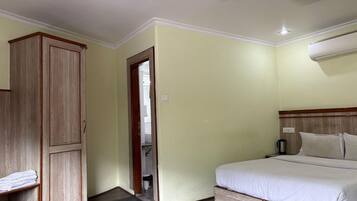 A bedroom with a bed, a wardrobe, a door leading to a bathroom, and a ceiling fan.