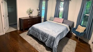 A bedroom with a bed, dresser, and a chair.