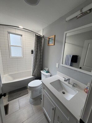 A modern bathroom with a bathtub, toilet, sink, and a window. - 3 Bedroom Condo - entire space (Boston)