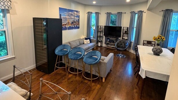 A modern living room with a sofa, TV, and bar stools.
