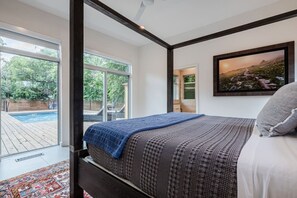 A bedroom with a large bed, a view of a swimming pool, and a framed picture on the wall. - Dreamy Modern Retreat: Pool + Sauna: Mins from DT (Austin)
