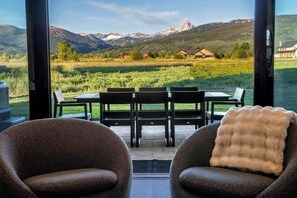 Ein Zimmer mit Blick auf die Berge, einem Tisch mit Stühlen und zwei Sesseln.