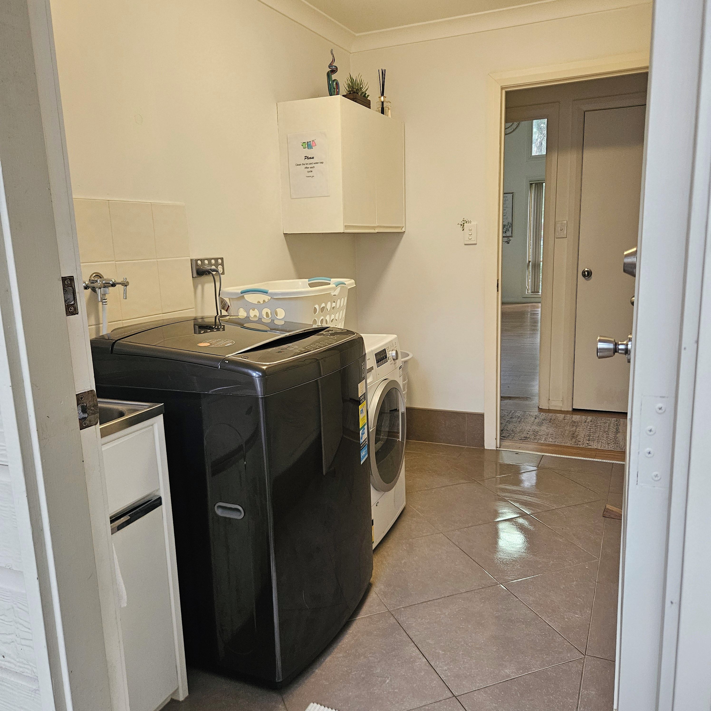 Ein Waschbereich mit Waschmaschine, Trockner und kleinem Kühlschrank.