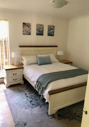 A bedroom with a bed, nightstands, a window, and wall art.