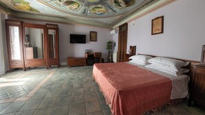 A room with a bed, a desk, a television, and a ceiling with artwork. - B&B Gioiosa (Gioiosa Ionica)