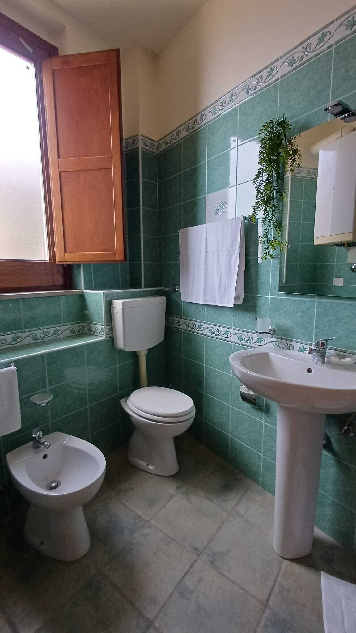 Ein Badezimmer mit Toilette, Bidet, Waschbecken und Spiegel.