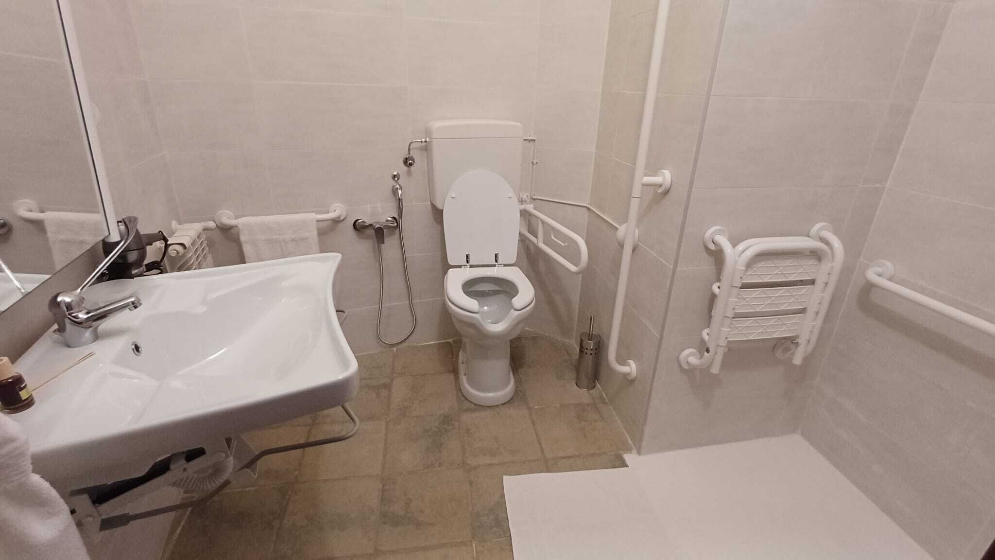 A bathroom with a white sink, toilet, and shower.