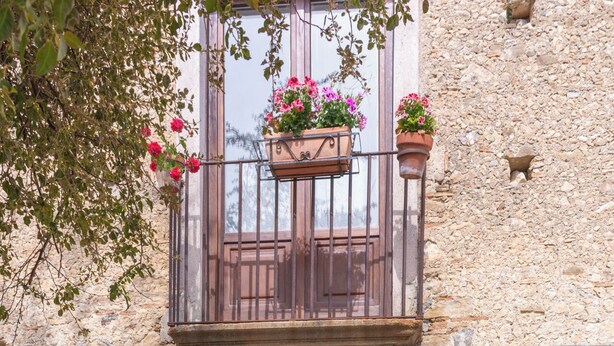 An entrance with a stone archway, a balcony with flower pots, and a number '17' sign. - B&B Gioiosa (Gioiosa Ionica)