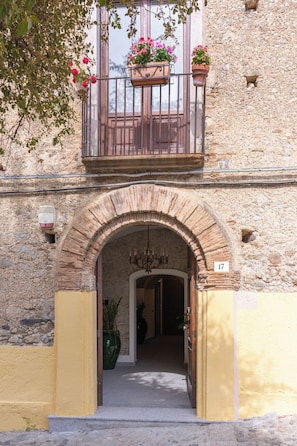 An entrance with a stone archway, a balcony with flower pots, and a number '17' sign.