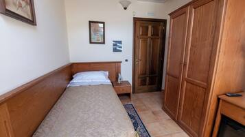 A bedroom with a bed, wooden wardrobe, and a tiled floor.