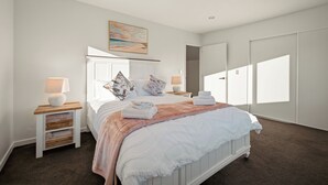 Ein Schlafzimmer mit einem Bett, Nachttischen, einem Gemälde und einem Kleiderschrank.