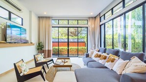A modern living room with a sofa, chairs, a coffee table, and a TV. - Premium 3BR Pool Villa In Cherngthalay (Choeng Thale)