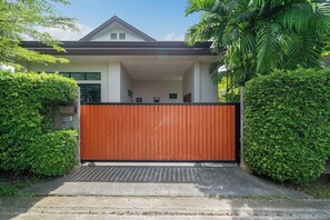 Ein modernes Haus mit einem befestigten Eingang, umgeben von üppiger Vegetation.