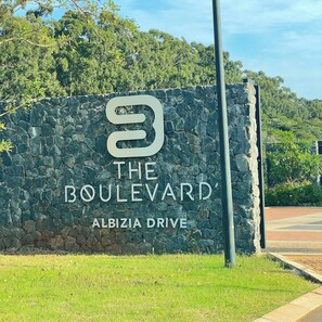 Eine Steinsäule mit einem Schild, auf dem 'The Boulevard' und 'Albizia Drive' stehen.