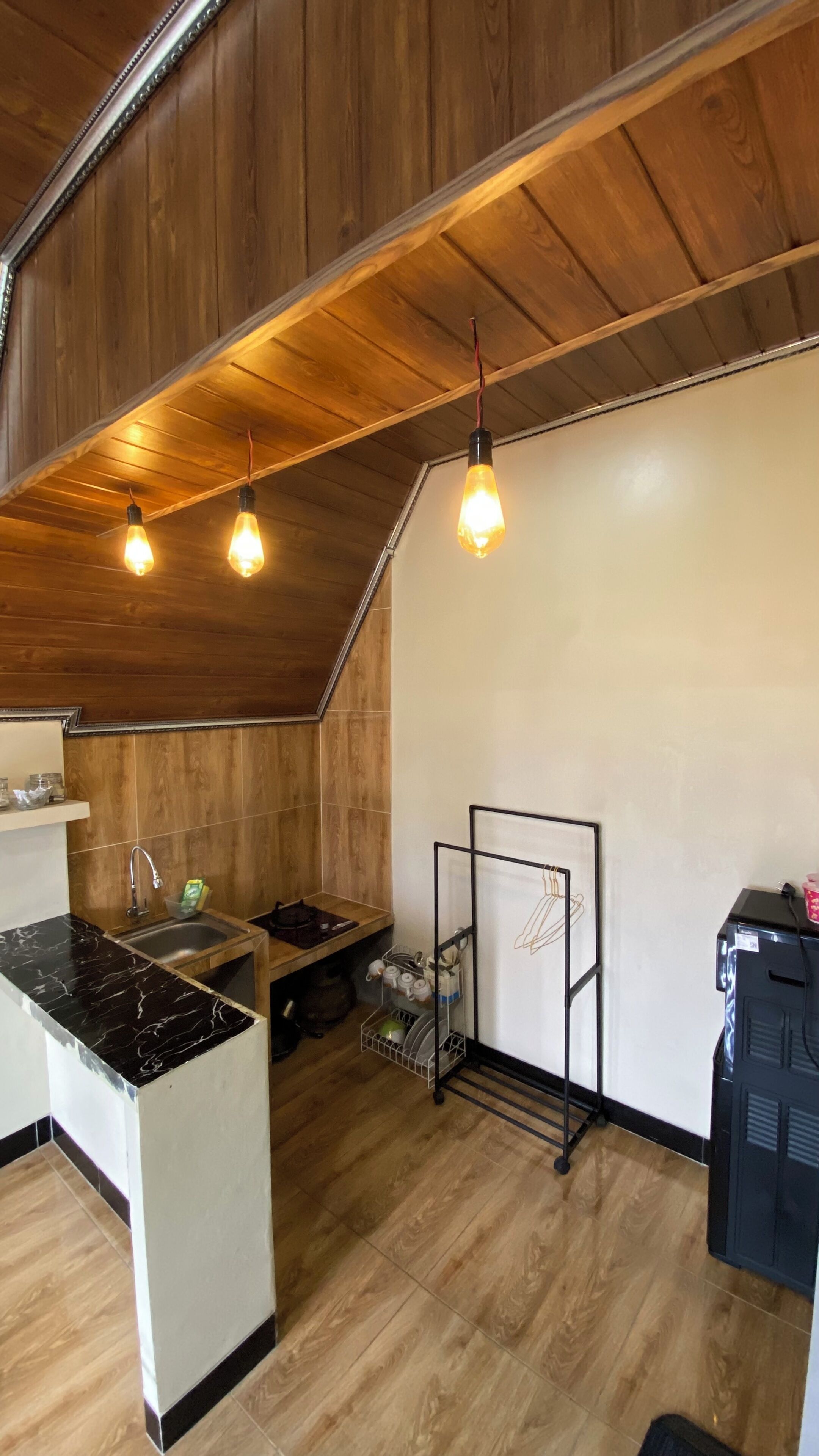 Una cocina con techo de madera, un lavamanos, una encimera y un escurreplatos con platos.