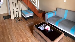 Amplia sala de estar con techo de madera, una escalera, un sofá y una mesa de centro.