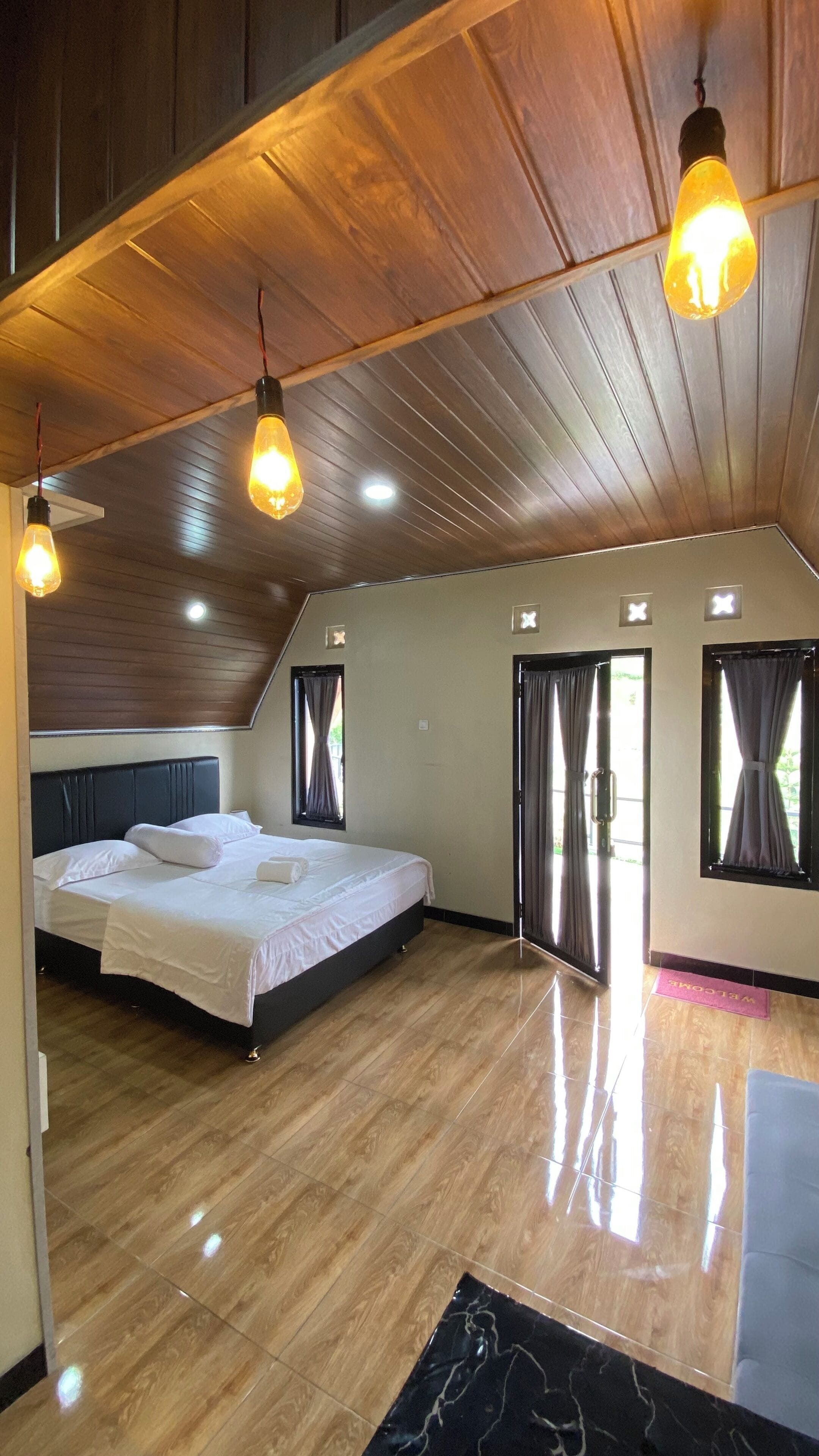 Un dormitorio con cama, techo de madera y piso pulido.