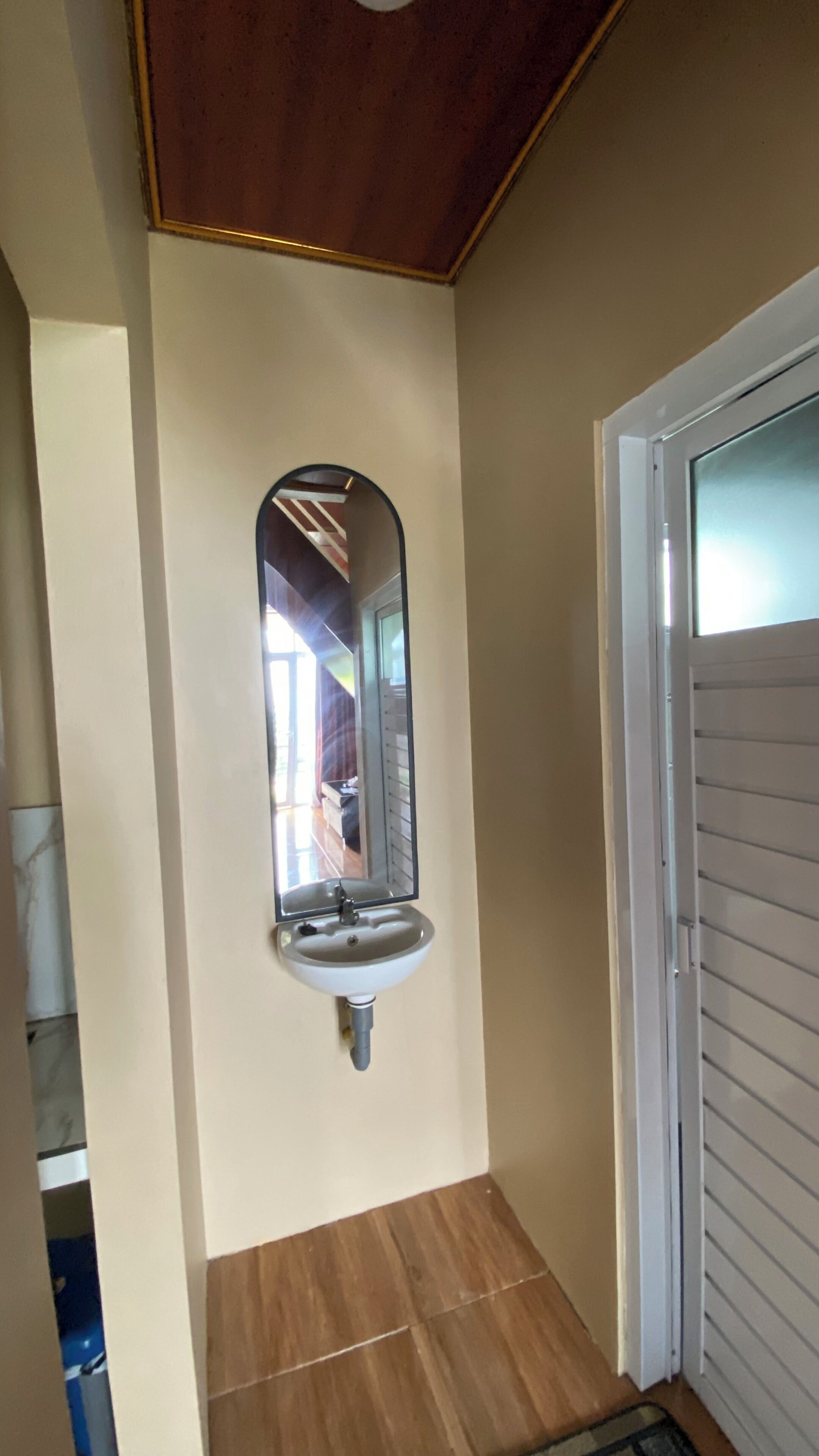 Baño con lavamanos, espejo y puerta.