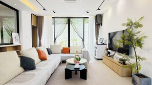 A modern living room with a sofa, coffee table, TV, and a potted plant. - NORD House J21 (Banglamung)