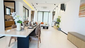 A modern dining area with a long table, chairs, and a vase of flowers. - NORD House J21 (Banglamung)