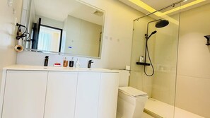A modern bathroom with a glass shower enclosure, a white vanity with cabinets, and a large mirror above the sink. - NORD House J21 (Banglamung)