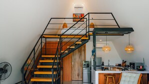 A modern interior with a staircase, kitchen, and seating area. - Dream Catcher Villas (Singaraja)