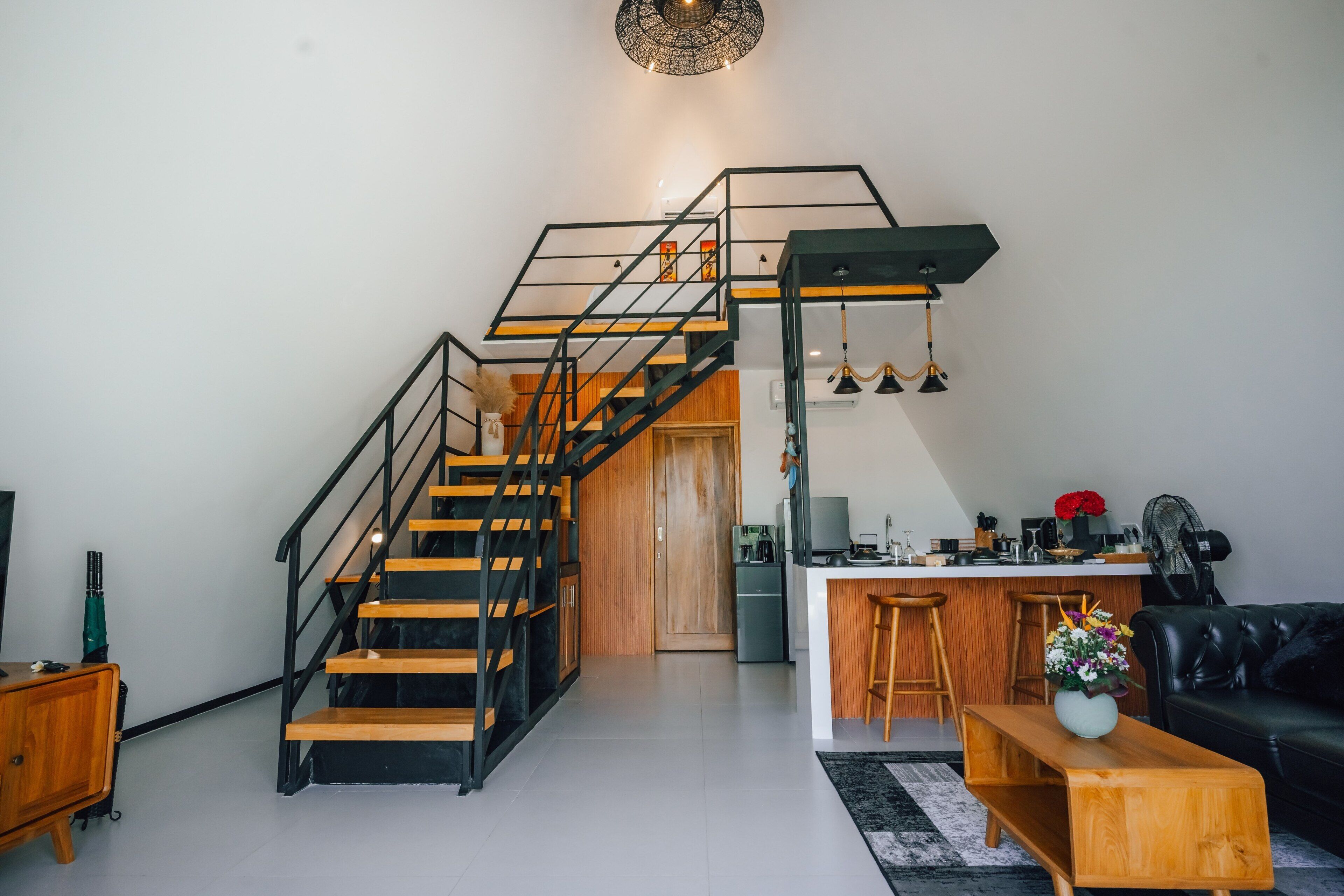 Un interior moderno con una escalera, cocina y zona de estar.