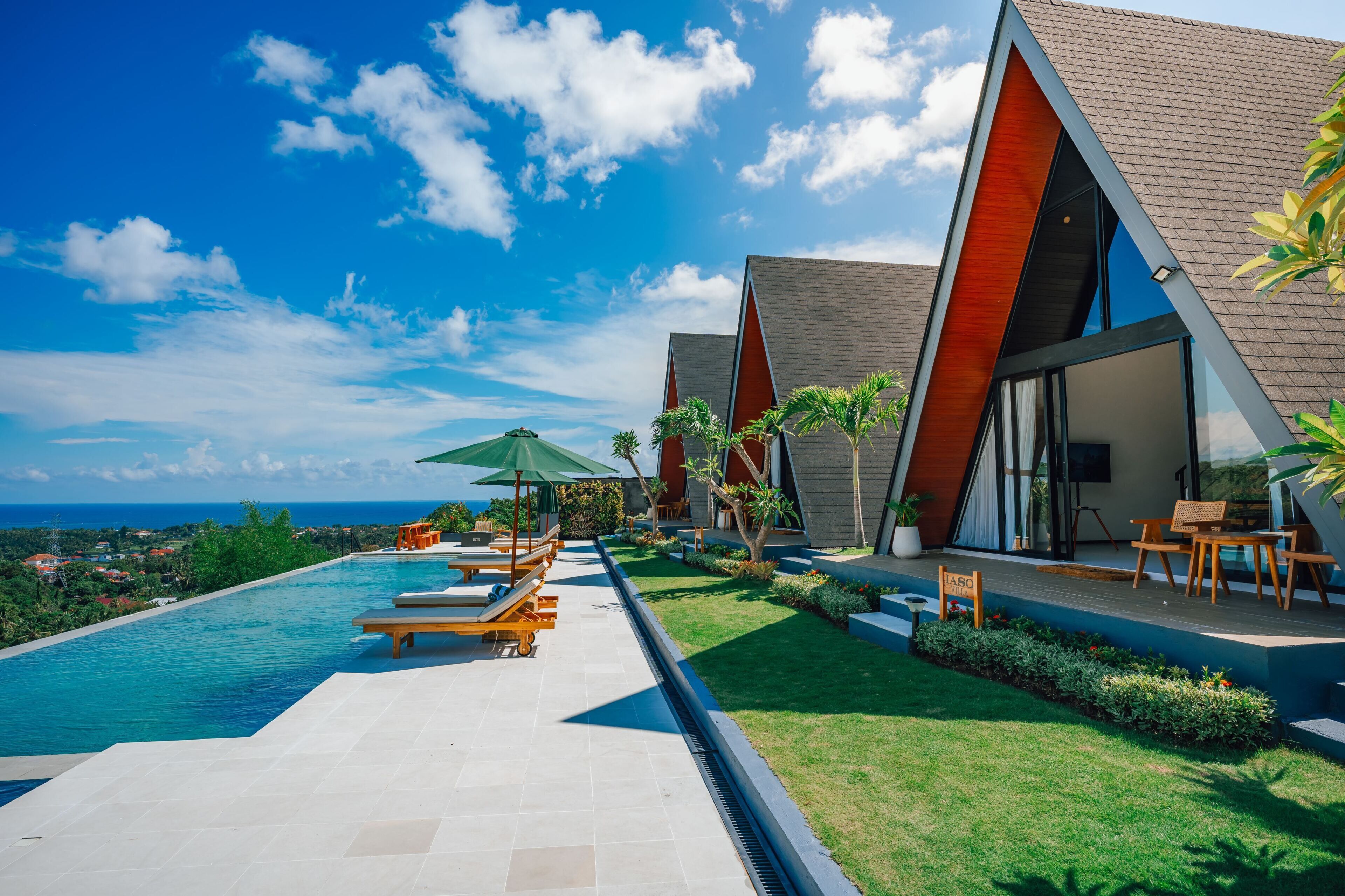 A modern resort with a swimming pool, outdoor seating, and a view of the ocean.