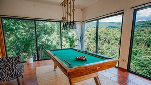 A pool table in a room with large windows overlooking a forested area. - Dream Catcher Villas (Singaraja)